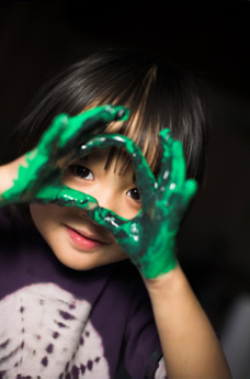 child looking through paint covered hands